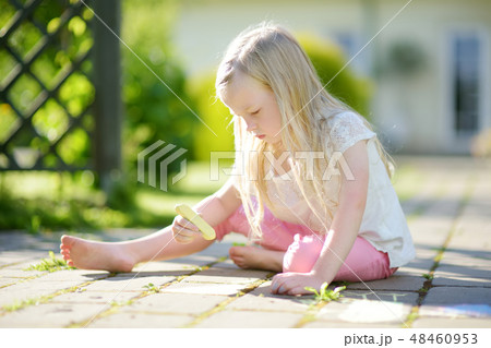 Cute little girl drawing with colorful chalks on a sidewalk. Summer activity for small kids. Cute little girl drawing with colorful chalks on a sidewalk. Summer activity for small kids. 48460953