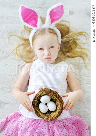 Cute little girl wearing bunny ears playing egg hunt on Easter Cute little girl wearing bunny ears playing egg hunt on Easter 48461537