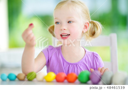 Cute little girl having fun with modeling clay at a daycare. Creative kid molding at home. Cute little girl having fun with modeling clay at a daycare. Creative kid molding at home. 48461539