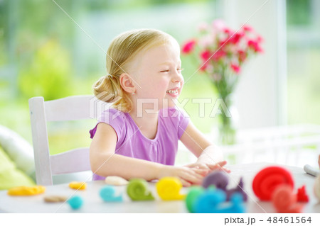 Cute little girl having fun with colorful modeling clay at a daycare 48461564