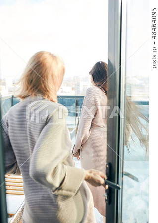 Two women standing in bathrobe on outdoor terrace with winter snowy cityscape 48464095