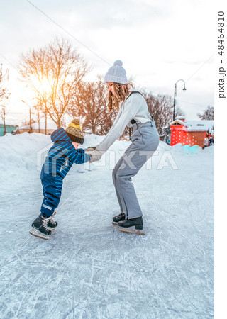 Young woman mom skates with her young son, a boy of 3-5 years. In the winter in the city on the rink 48464810