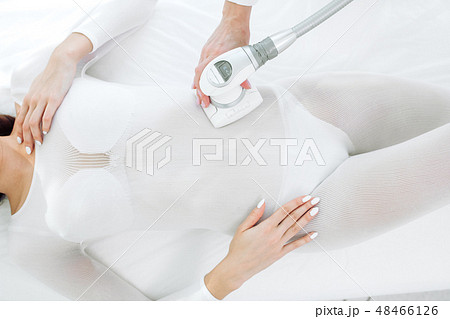 close up beauty specialist doing LPG apparatus massage on female belly 48466126