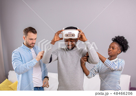Multicultural friends help african guy to manade with vr headset for fist time 48466206