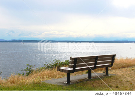 Park Bench by blue sea and sky view Park Bench by blue sea and sky view 48467844