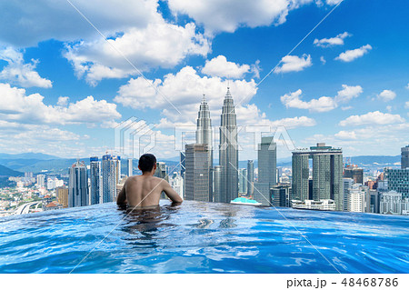 Back of tourist in a swimming pool on rooftop with Kuala Lumpur 48468786