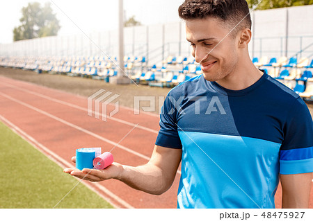 Young man on stadium outside standing with kinesio tape smiling cheerful close-up 48475927