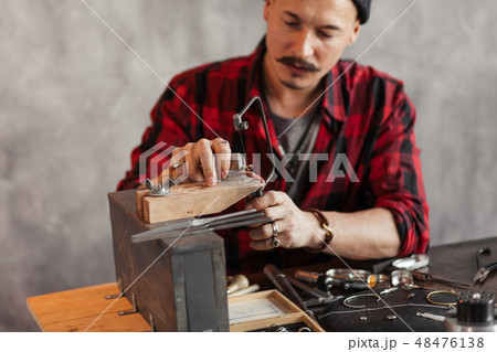 handsome craftsman using fret saw in the workshop 48476138