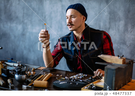 young attractive artisan checking the quality of amber in the jewellery shop 48477337