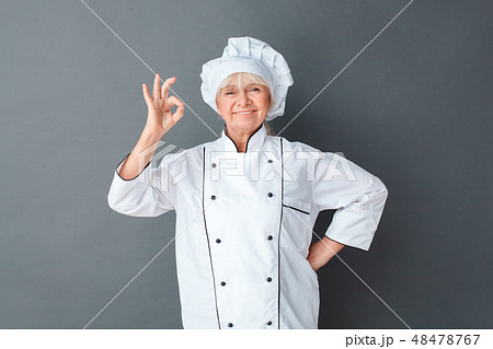 Senior woman chef studio standing isolated on gray posing showing ok cheerful 48478767