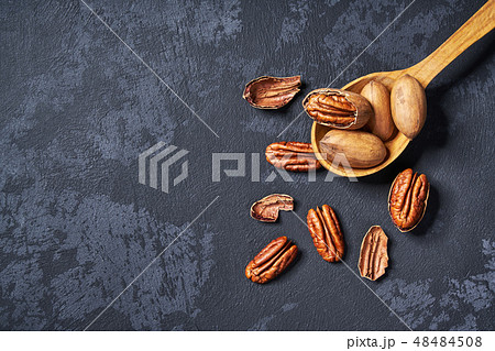 Pecan in wooden spoon on black table. Pecan in wooden spoon on black table. 48484508