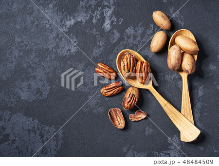 Pecan in two wooden spoons on black table. 48484509