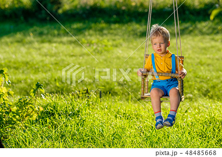 Rural scene with toddler boy swinging outdoors. Rural scene with toddler boy swinging outdoors. 48485668