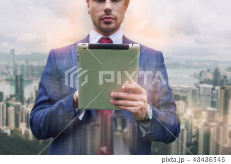 Confident IT expert. Close-up portrait of businessman in suit using digital tablet while standing 48486546