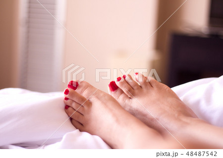Feet of woman with red painted nails on the bed 48487542