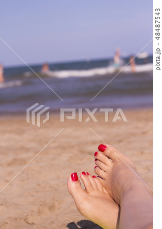 Feet of woman with nails painted red on the sand 48487543