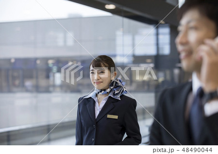 空港内の通路を歩くCAとスマホで通話をするビジネスマン 48490044