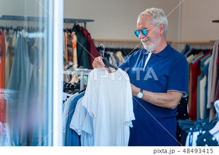 Delighted grey haired man choosing new outfit Delighted grey haired man choosing new outfit 48493415