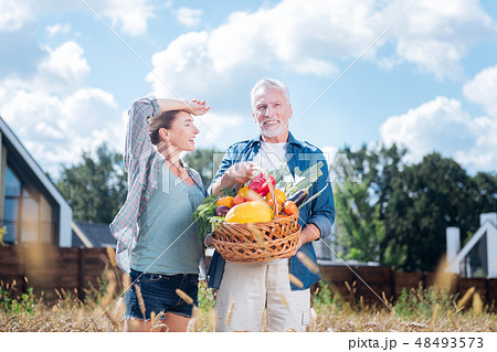 Smiling blonde-haired wife feeling satisfied after gathering harvest with husband 48493573