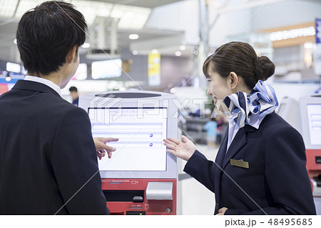 空港で自動チェックイン機の使い方を教わるビジネスマン 48495685
