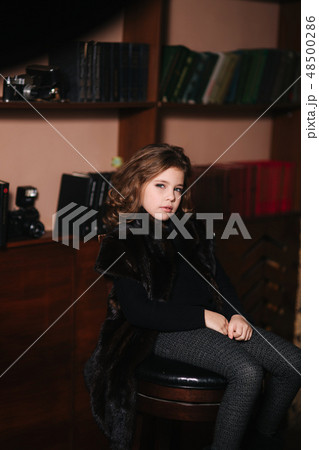 Beautiful little girl is reading a book in the library. Preparing for a school 48500286