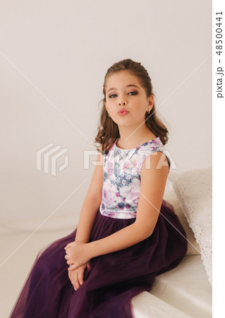 Beautiful girl in a purple dress and flower blouse posing for a photographer 48500441