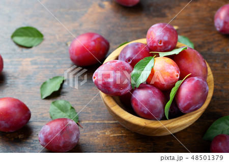 Wooden plate with ripe juicy plums on table. 48501379