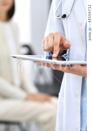 Female physician using digital tablet while standing near reception desk at clinic or emergency 48504732