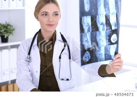 Doctor woman examining x-ray picture near window in hospital. Surgeon or orthopedist at work 48504873