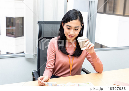 コーヒーを飲みながら雑誌を見ている女性 コーヒーを飲みながら雑誌を見ている女性 48507088