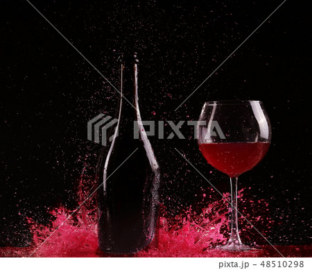 Glass and bottle of red wine splash on black Glass and bottle of red wine splash on black 48510298