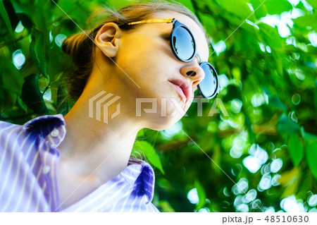 Portrait of a Young Woman in Sunglasses in Foliage 48510630