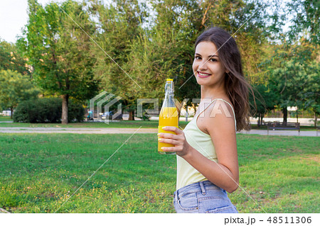 Young girl is walking in the park holding a bottle 48511306