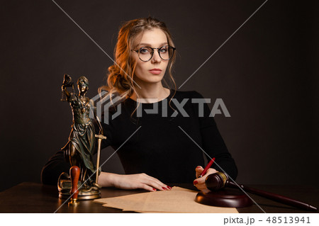 Pretty young woman in a glasses and in a black dress sitting and wrighting importaint document 48513941