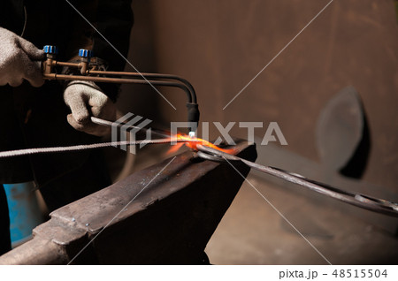 Close-up - Hands Of A Blacksmith Weld Elements To Their Forged Product 48515504