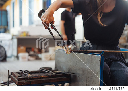 A glassblower student tries to make a flower out of glass 48518535
