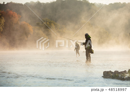 Men fishing in river with fly rod during summer morning. 48518997