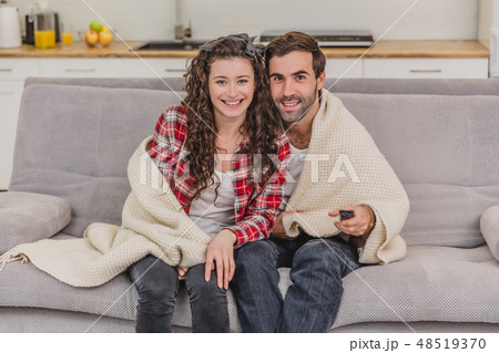 Young couple relaxing in their apartment, lying on the couch, watching a movie. Young couple relaxing in their apartment, lying on the couch, watching a movie. 48519370