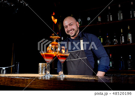Fiery show at the bar. The bartender makes hot alcoholic cocktail and ignites bar. Bartender 48520196