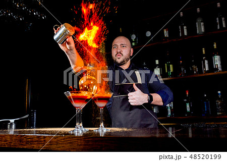 Fiery show at the bar. The bartender makes hot alcoholic cocktail and ignites bar. Bartender 48520199