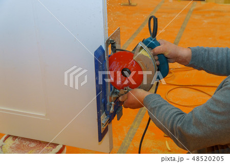 Contractor using a electric saw to cut door 48520205