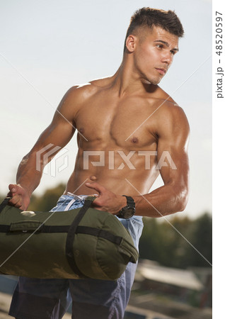 Portrait of handsome man training at the beach with sand bag equipment. Portrait of handsome man training at the beach with sand bag equipment. 48520597