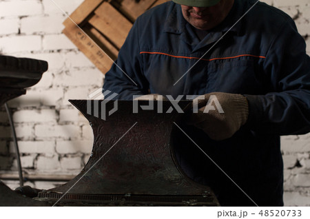Blacksmith in workshop soldering metal object Blacksmith in workshop soldering metal object 48520733