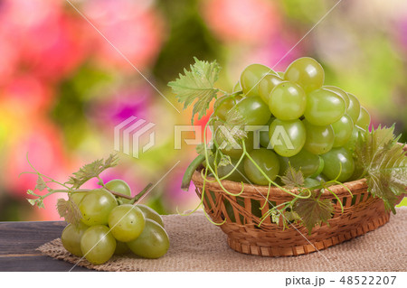 green grapes in a wicker basket on wooden table with blurred background 48522207