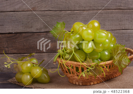 green grapes in a wicker basket on wooden table 48522368
