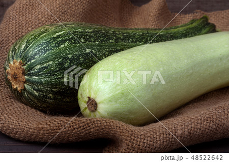 green zucchini and courgette on sackcloth wooden background green zucchini and courgette on sackcloth wooden background 48522642