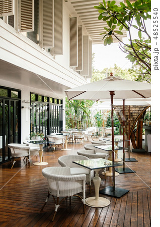 Rattan chairs, dining tables and white umbrellas 48525540