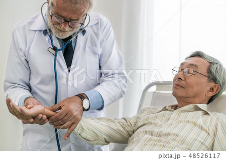 Mature doctor and senior patient in hospital ward. Mature doctor and senior patient in hospital ward. 48526117