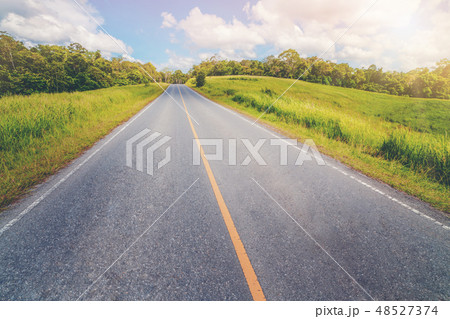 Highway road through green grass under blue sky. Highway road through green grass under blue sky. 48527374