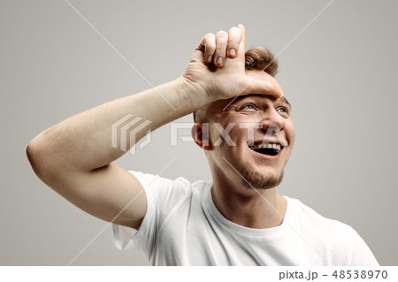 Losers go home. Portrait of happy guy showing loser sign over forehead Losers go home. Portrait of happy guy showing loser sign over forehead 48538970